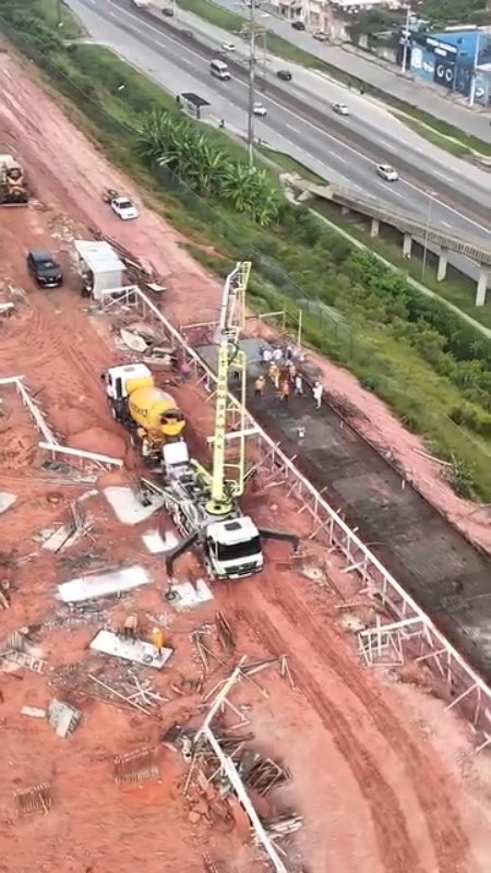 Vista aérea de concretagem com caminhão-bomba ao lado de uma rodovia
